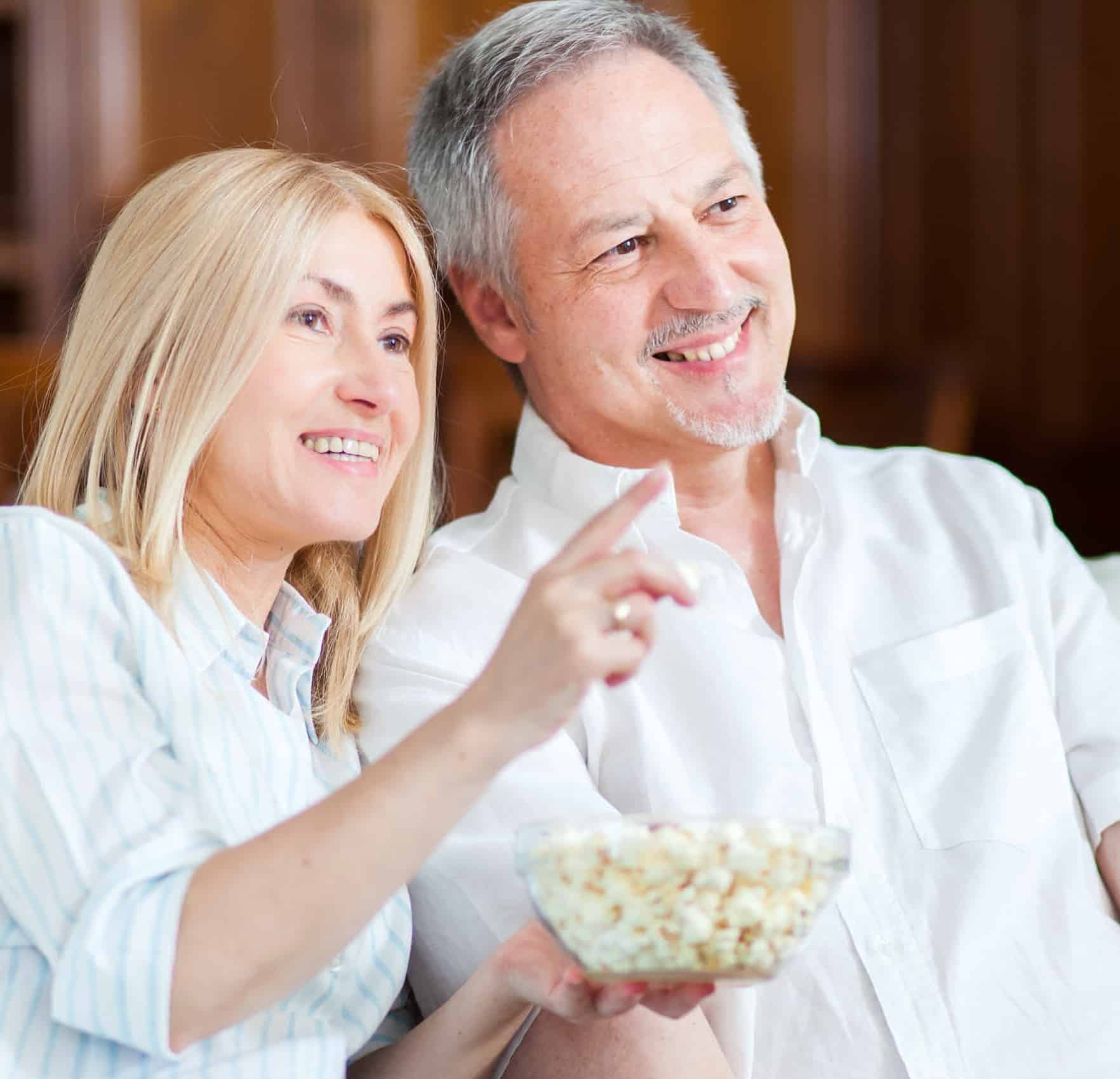 Couple eating popcorn watching a movie on their TV